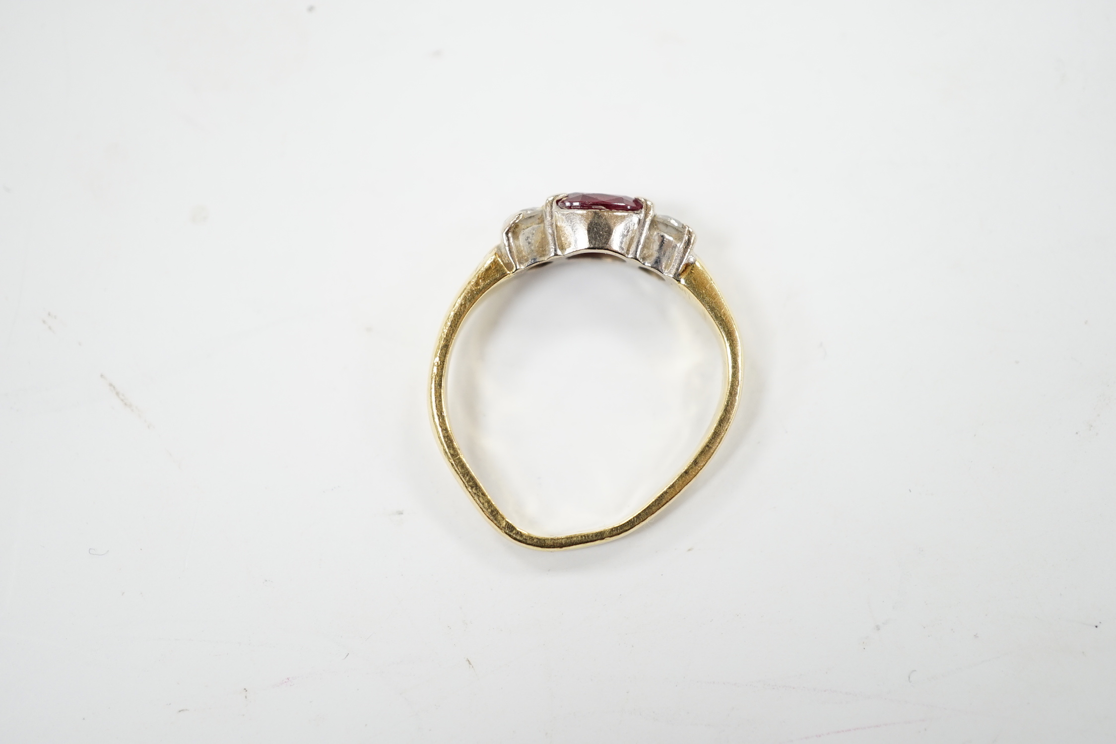 A modern 18ct gold, ruby and diamond set three stone ring, shank misshapen, gross weight 2.9 grams.